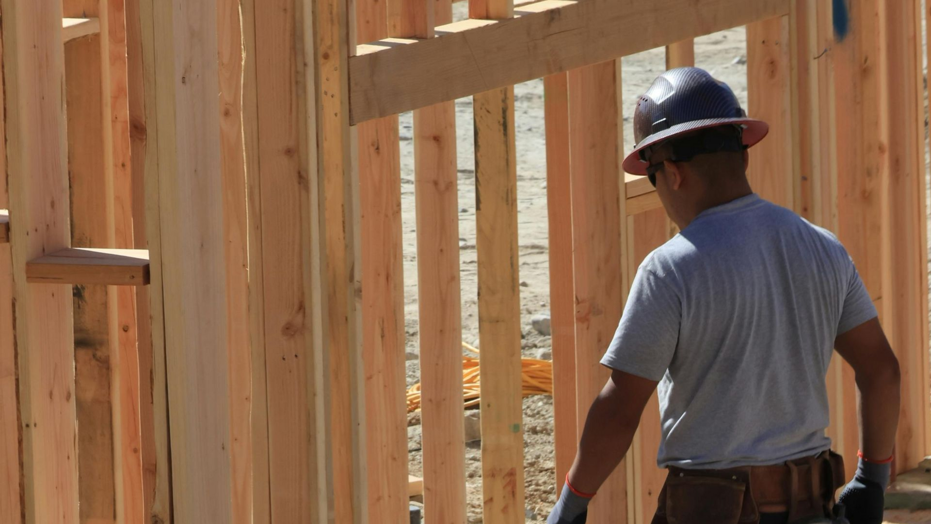 Two-story beige house with black roof and brown garage doors. Evening sky.