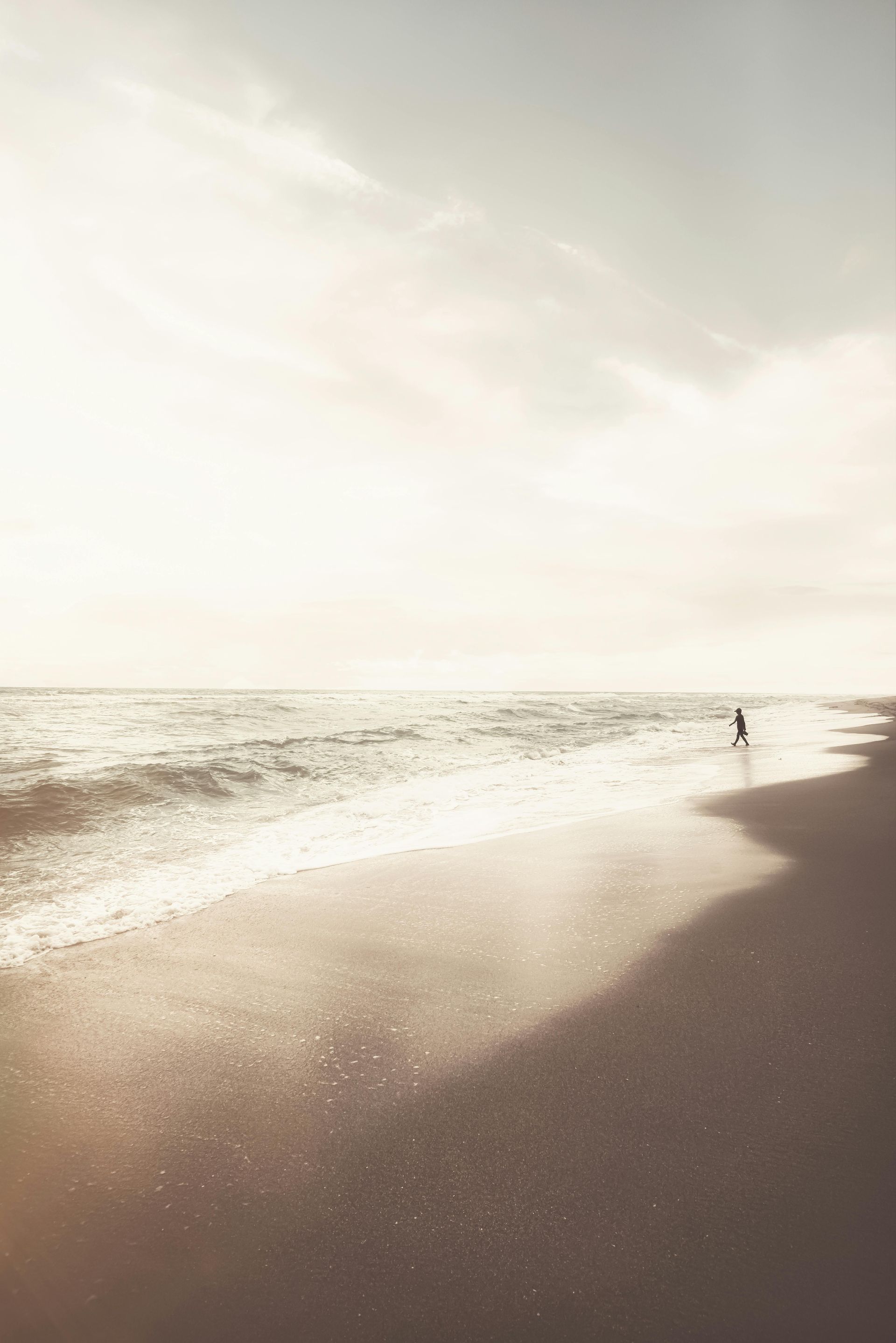 A person is walking on a beach near the ocean.