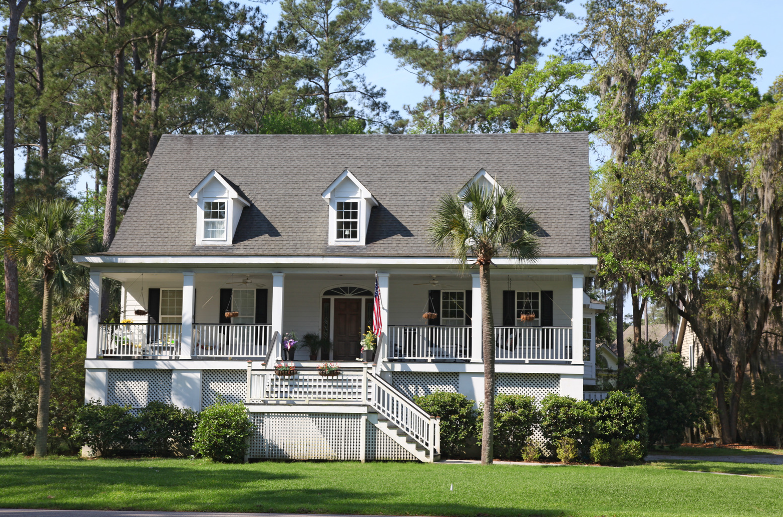 A white house with a gray roof and a large porch