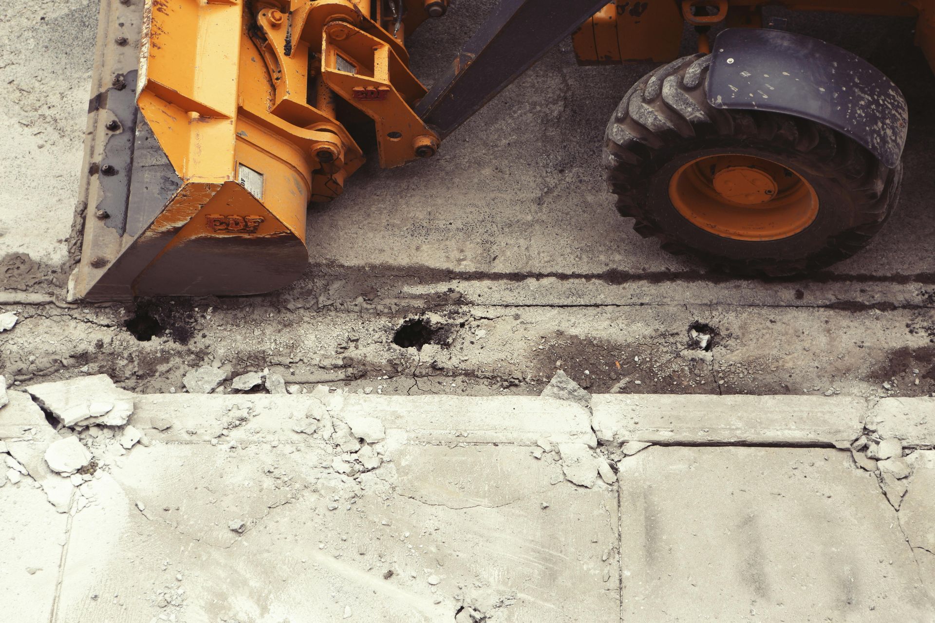 A bulldozer is digging a hole in the sidewalk.