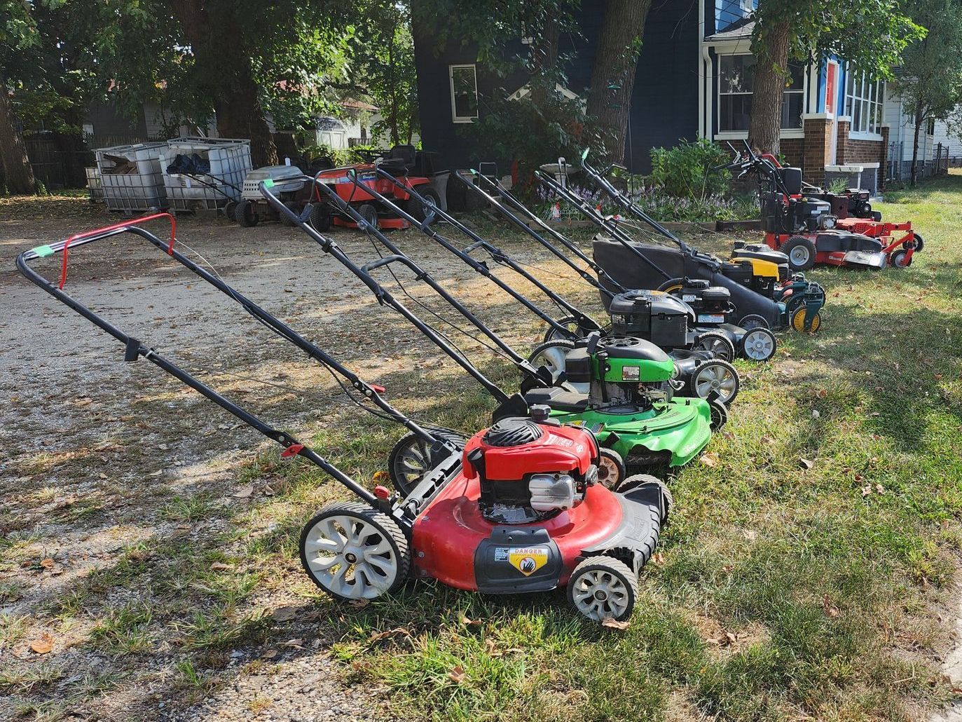 A row of lawn mowers are lined up in a store.