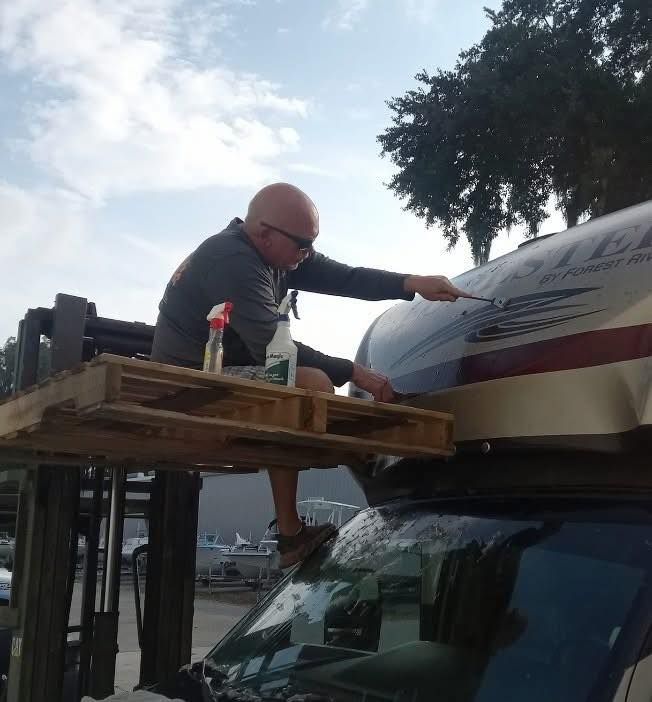 Person securing a covered load on top of a vehicle using a strap on a work platform