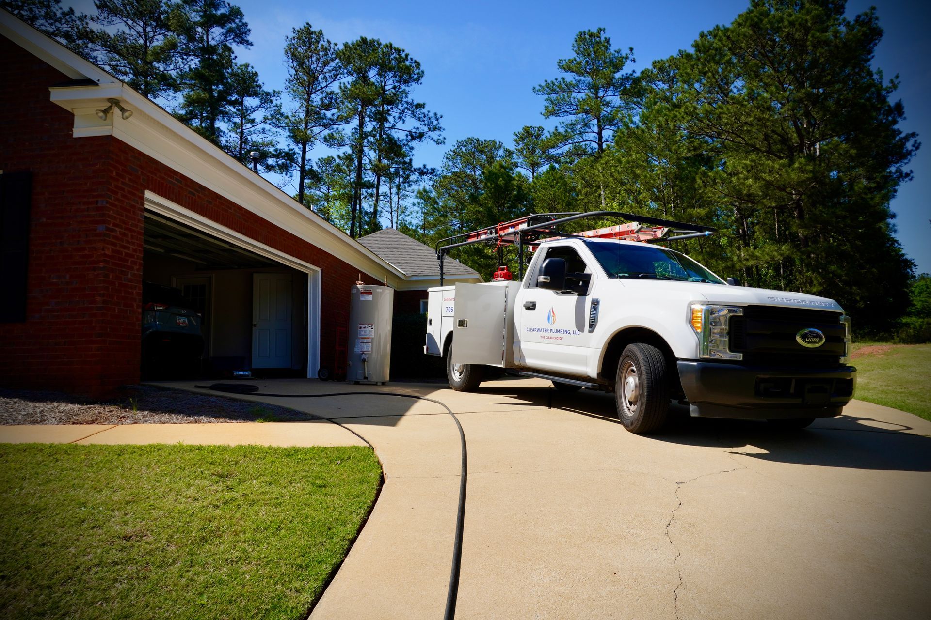 White service truck parked near a brick house garage; a worker is visible inside.