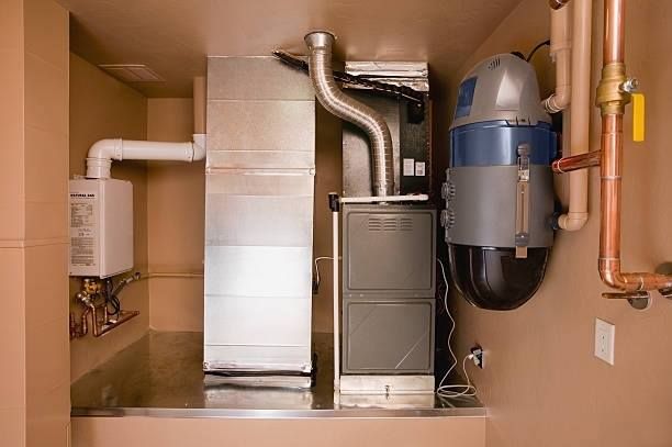 Outdoor air conditioner unit with blue buckets and hoses beside a wall