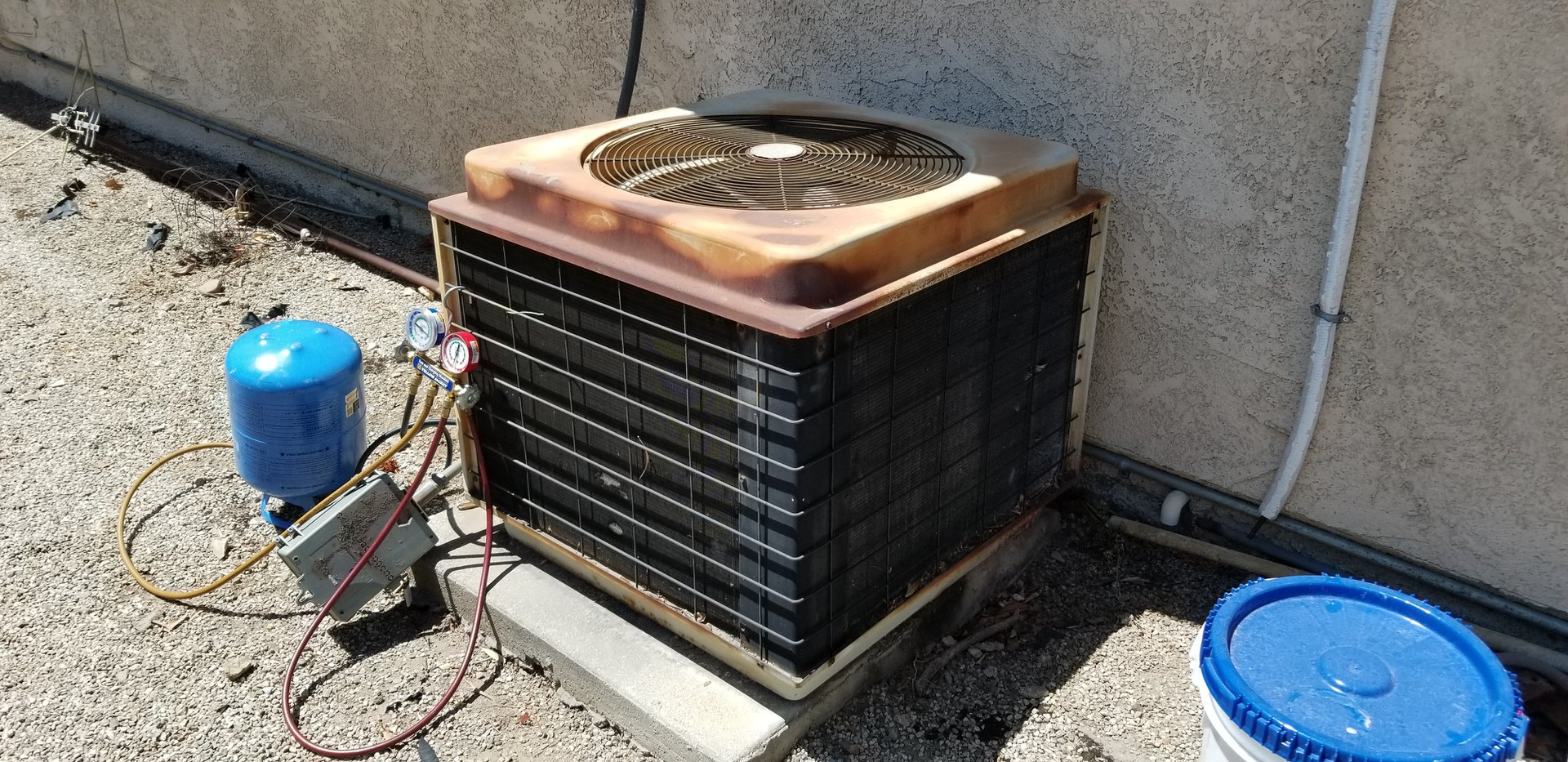 Woman in straw hat smiles, holding wine glass near a lake.