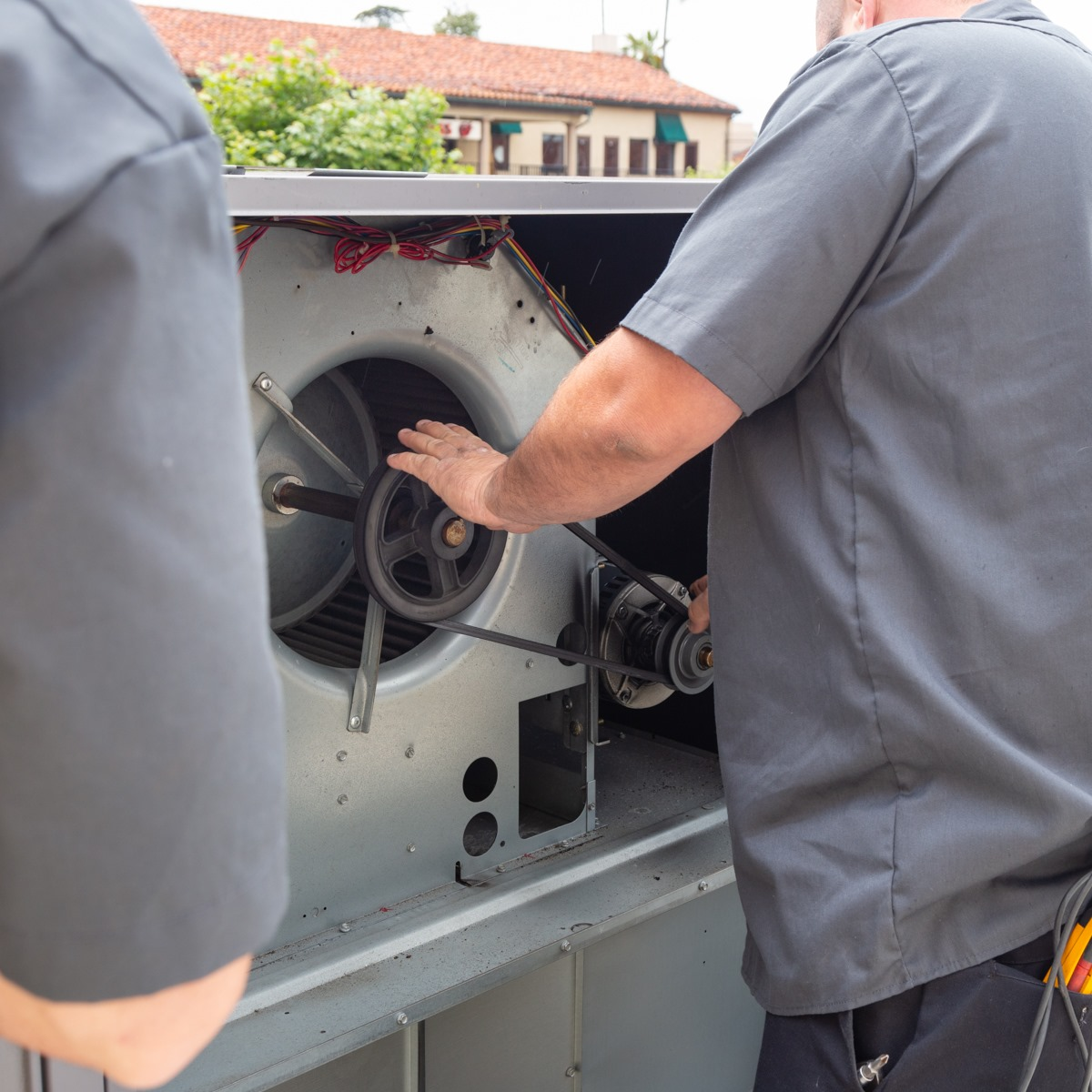 Woman in straw hat smiles, holding wine glass near a lake.