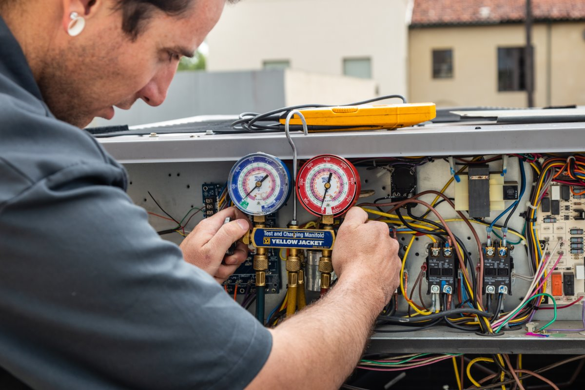 Woman in straw hat smiles, holding wine glass near a lake.