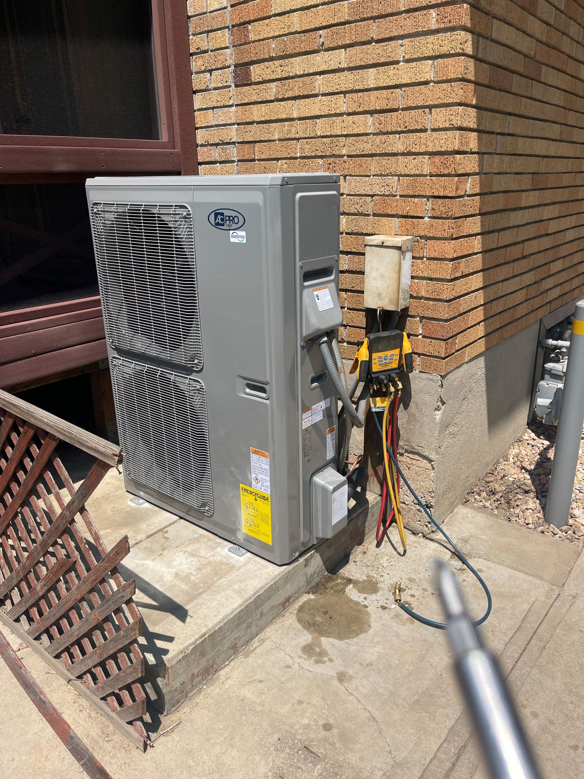 Two technicians inspecting the open fan compartment of a large HVAC unit outdoors.