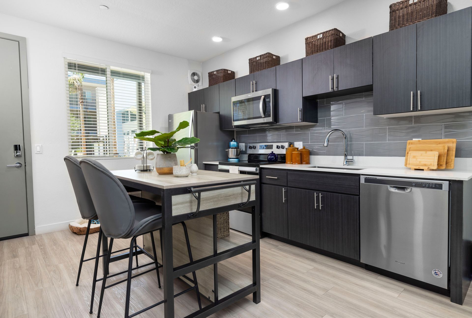 Modern kitchen with dark cabinets, stainless steel appliances, and a breakfast bar.