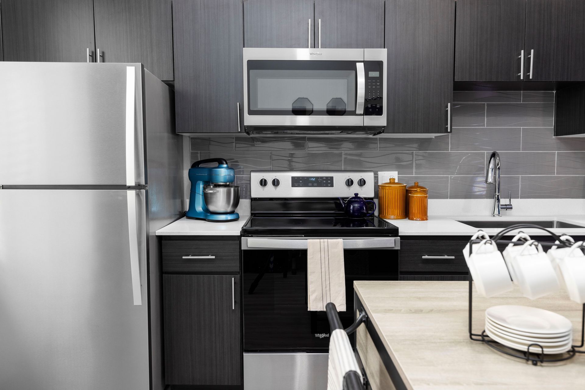 Modern kitchen with stainless steel appliances and dark cabinets.
