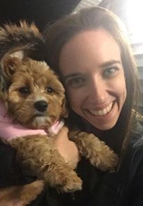 A woman is holding a small brown dog in her arms.