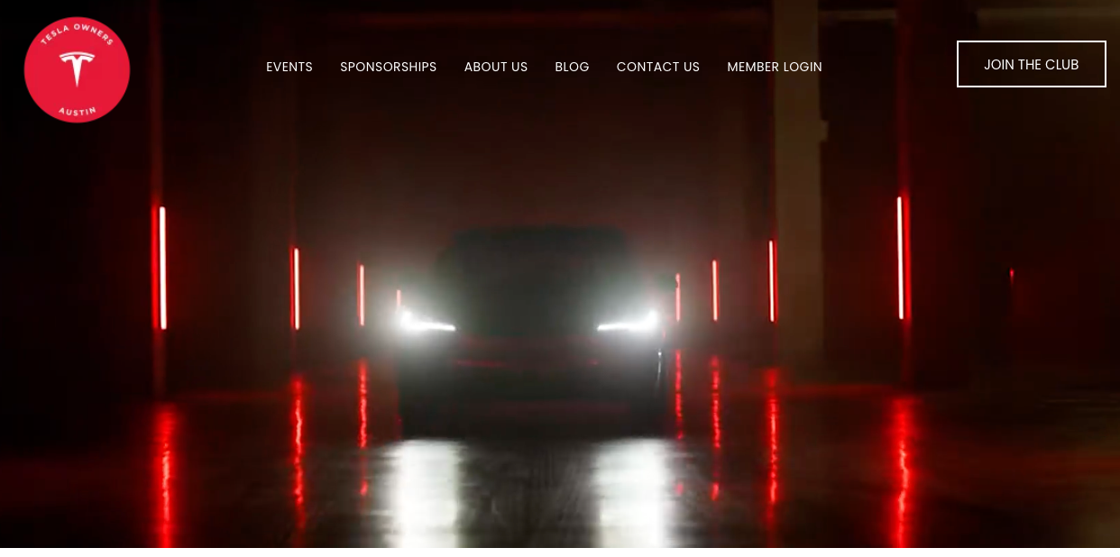 A tesla model s is driving through a dark parking garage.