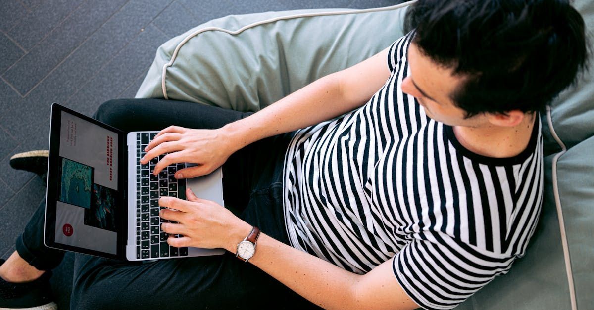 A man is sitting on a bean bag chair using a laptop computer.