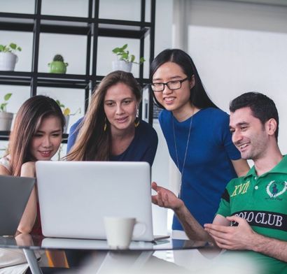 A group of people are looking at a laptop and one of them is wearing a polo club shirt