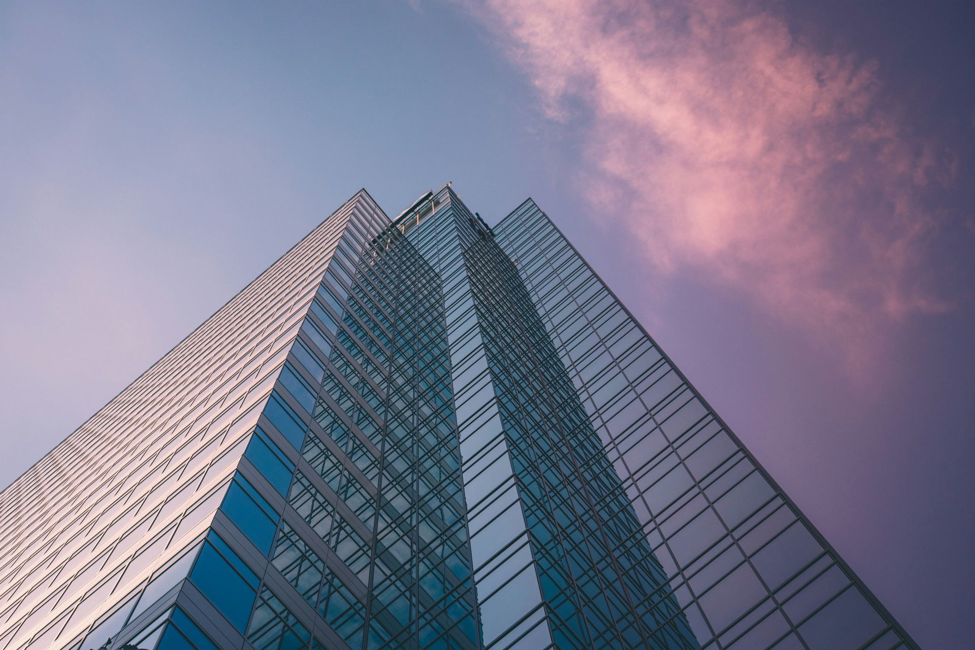 Looking up at a tall building with a cloudy sky in the background.