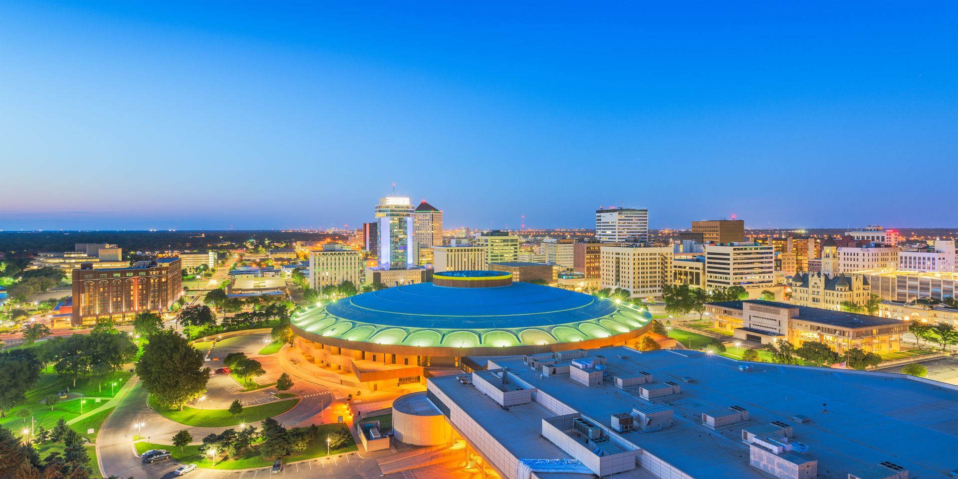 An aerial view of a city at night with a large dome in the middle of the city.
