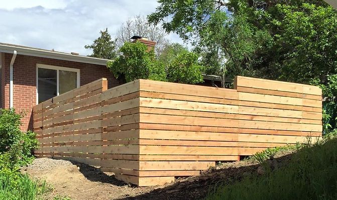 A wooden fence is in front of a brick house.