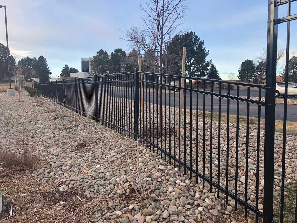 A black metal fence is surrounded by gravel and rocks.