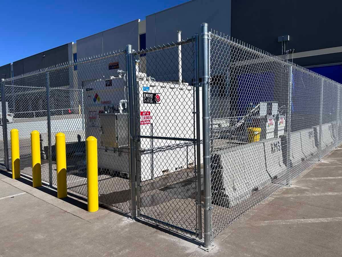 A chain link fence is surrounding a building and a container.