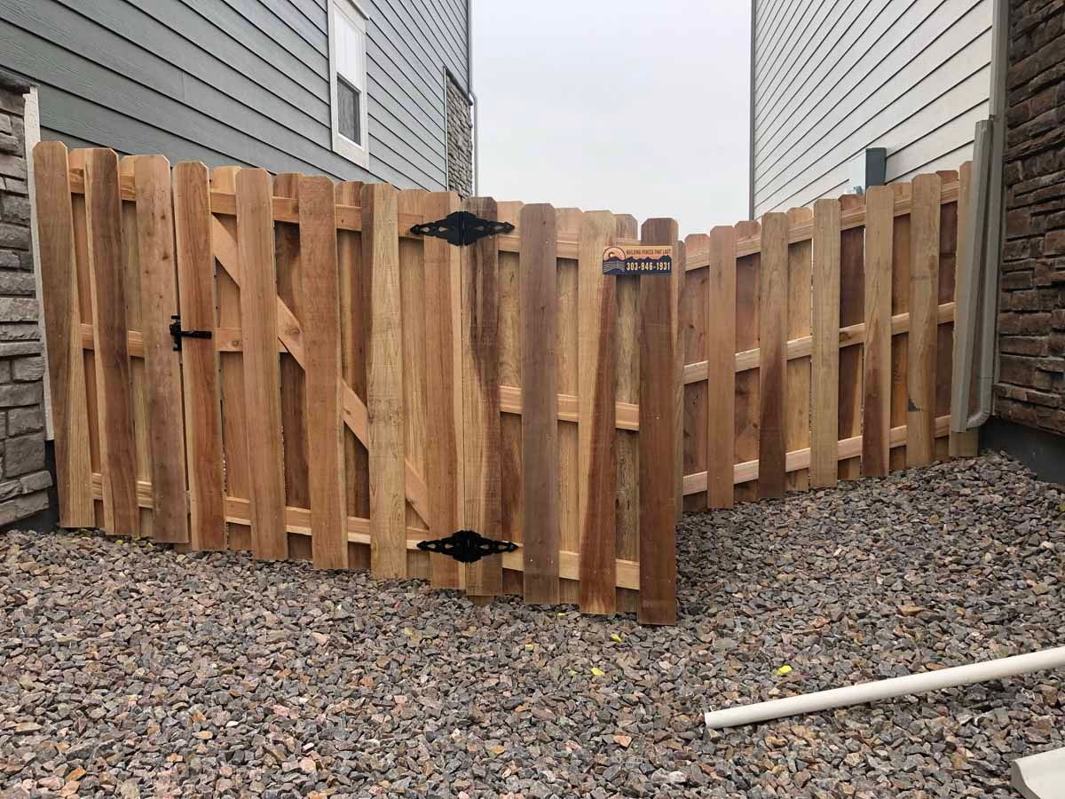A wooden fence is sitting on top of a pile of gravel in front of a house.