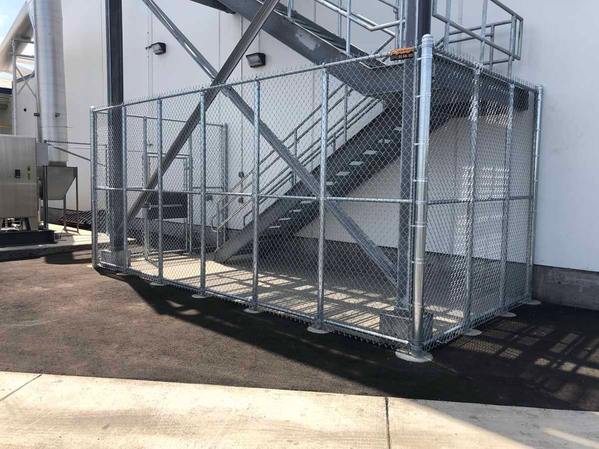 A chain link fence is surrounding a staircase on the side of a building.