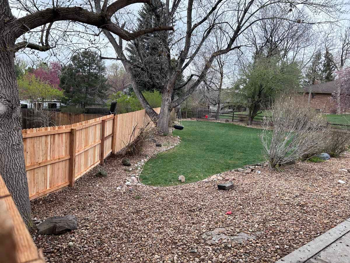 A wooden fence surrounds a lush green yard.