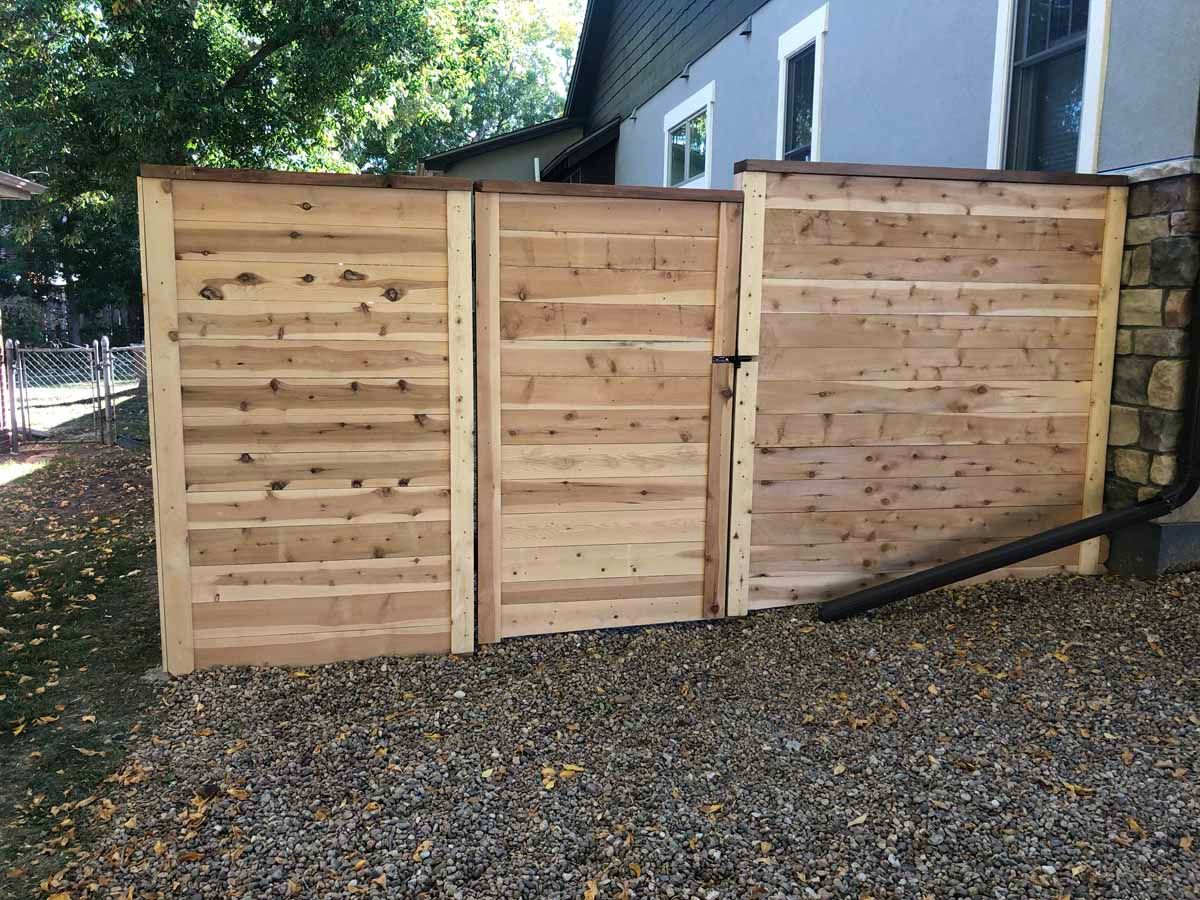 A wooden fence with a gate in front of a house.
