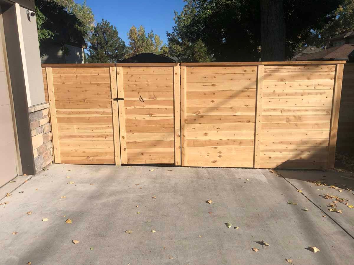 A wooden fence is sitting in a driveway next to a garage.