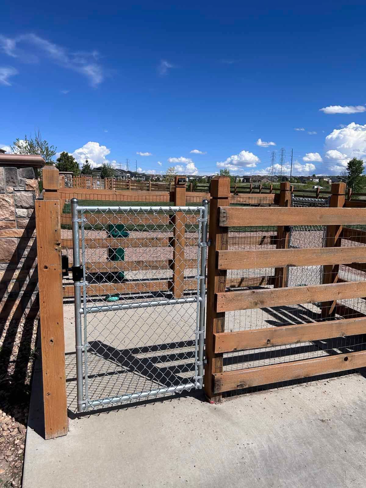 A wooden fence with a chain link fence and a gate.