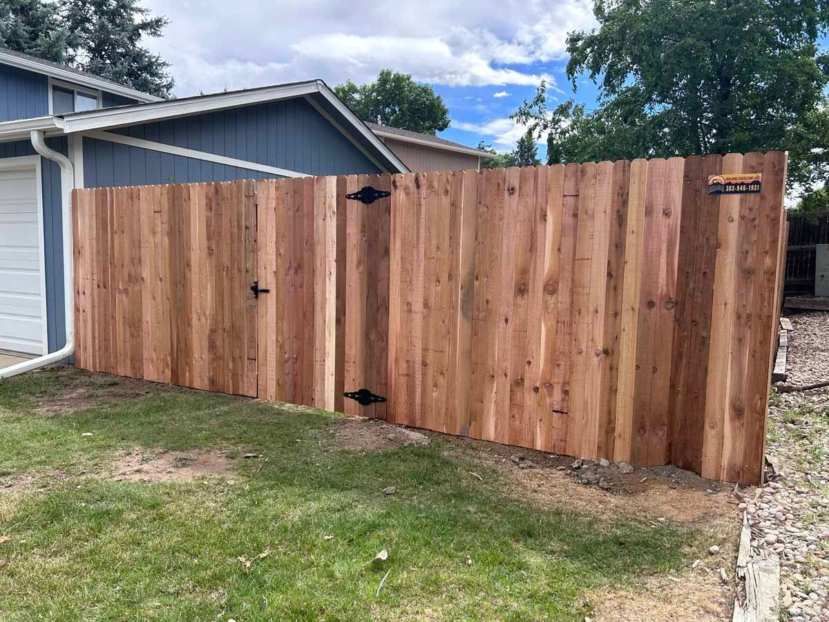 A wooden fence with a gate in front of a house.