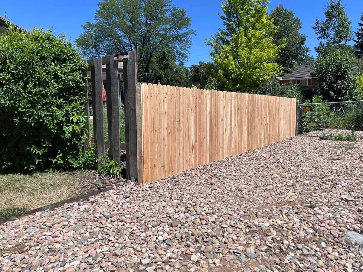 A wooden fence is sitting on top of a pile of gravel.