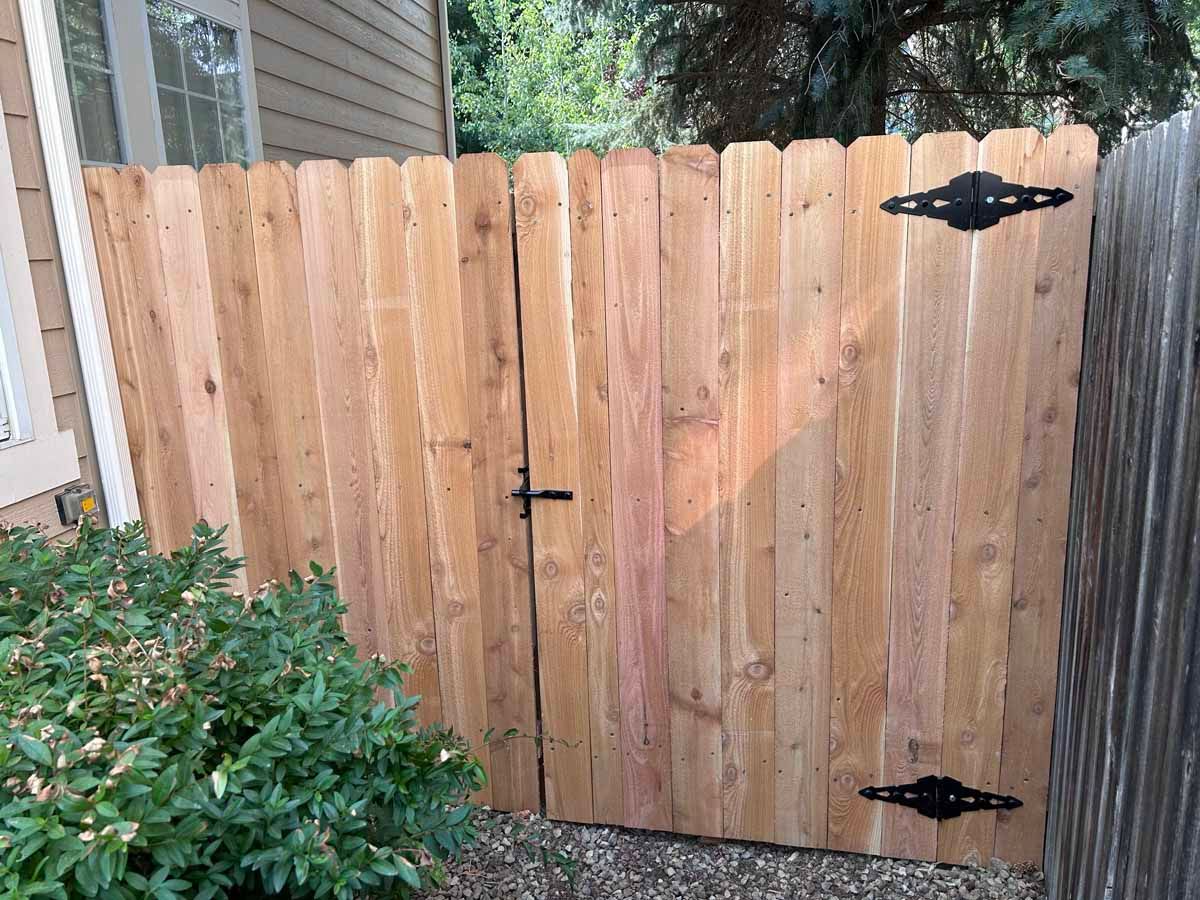 A wooden fence with a gate in front of a house.