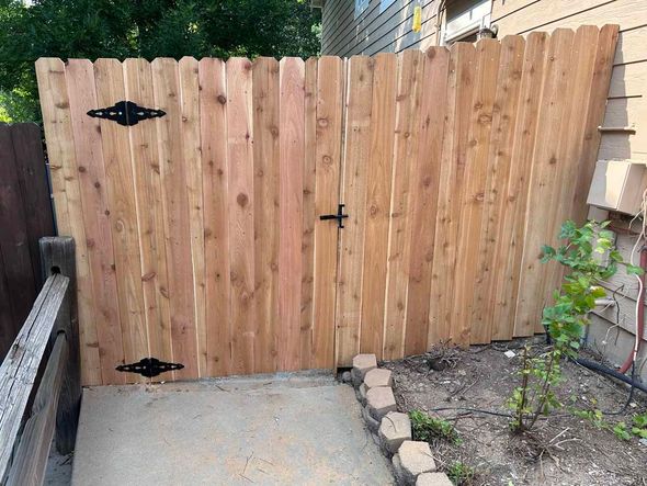 A wooden fence with a gate in the backyard of a house.