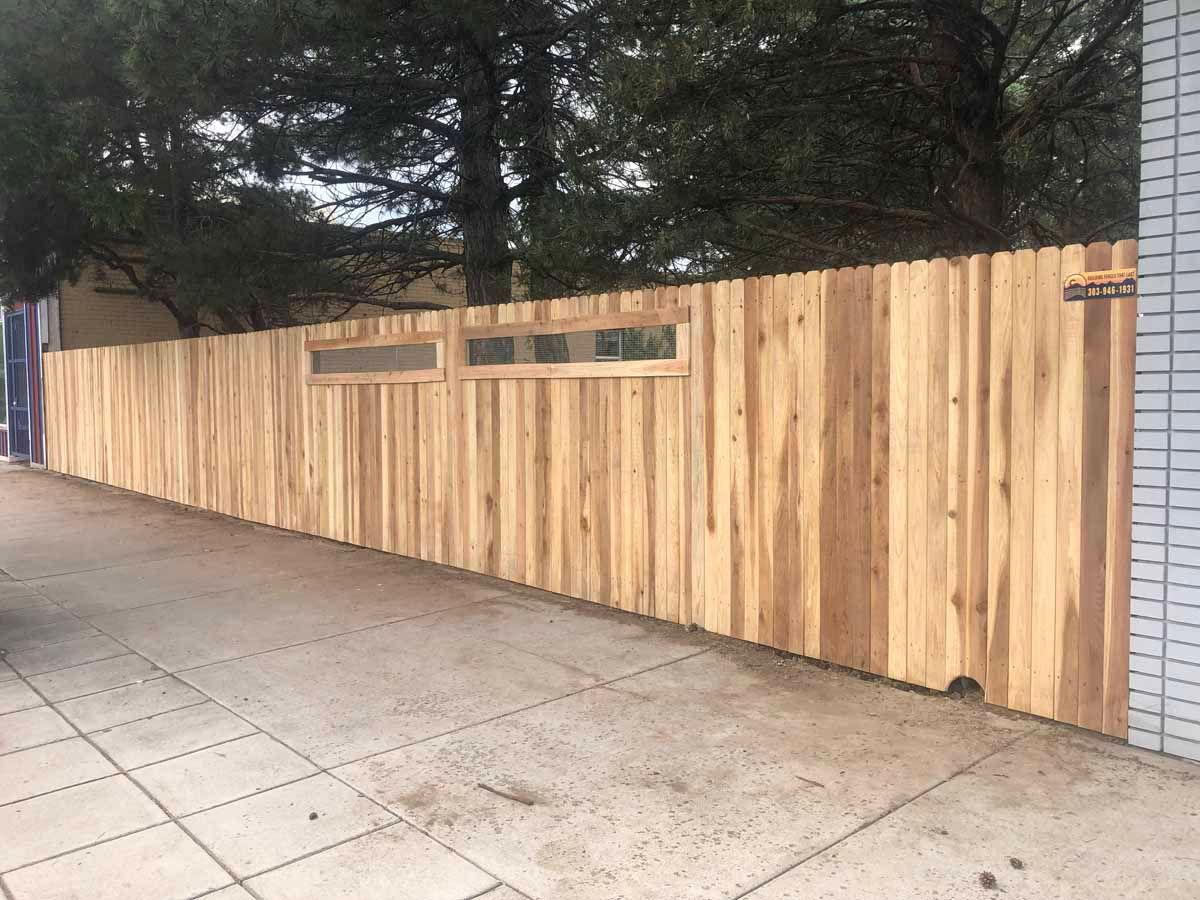 A wooden fence is sitting on the sidewalk next to a building.