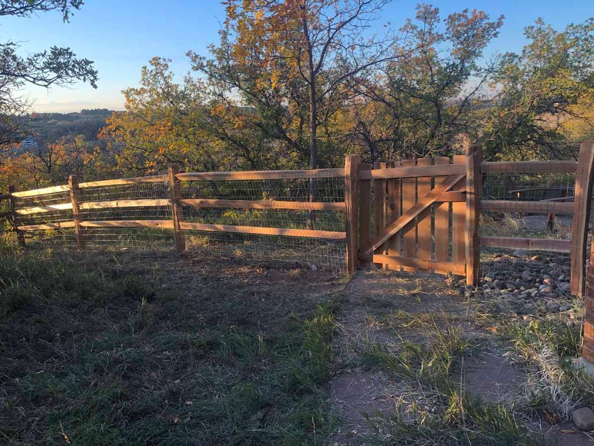 A wooden fence with a gate in the middle of a field.