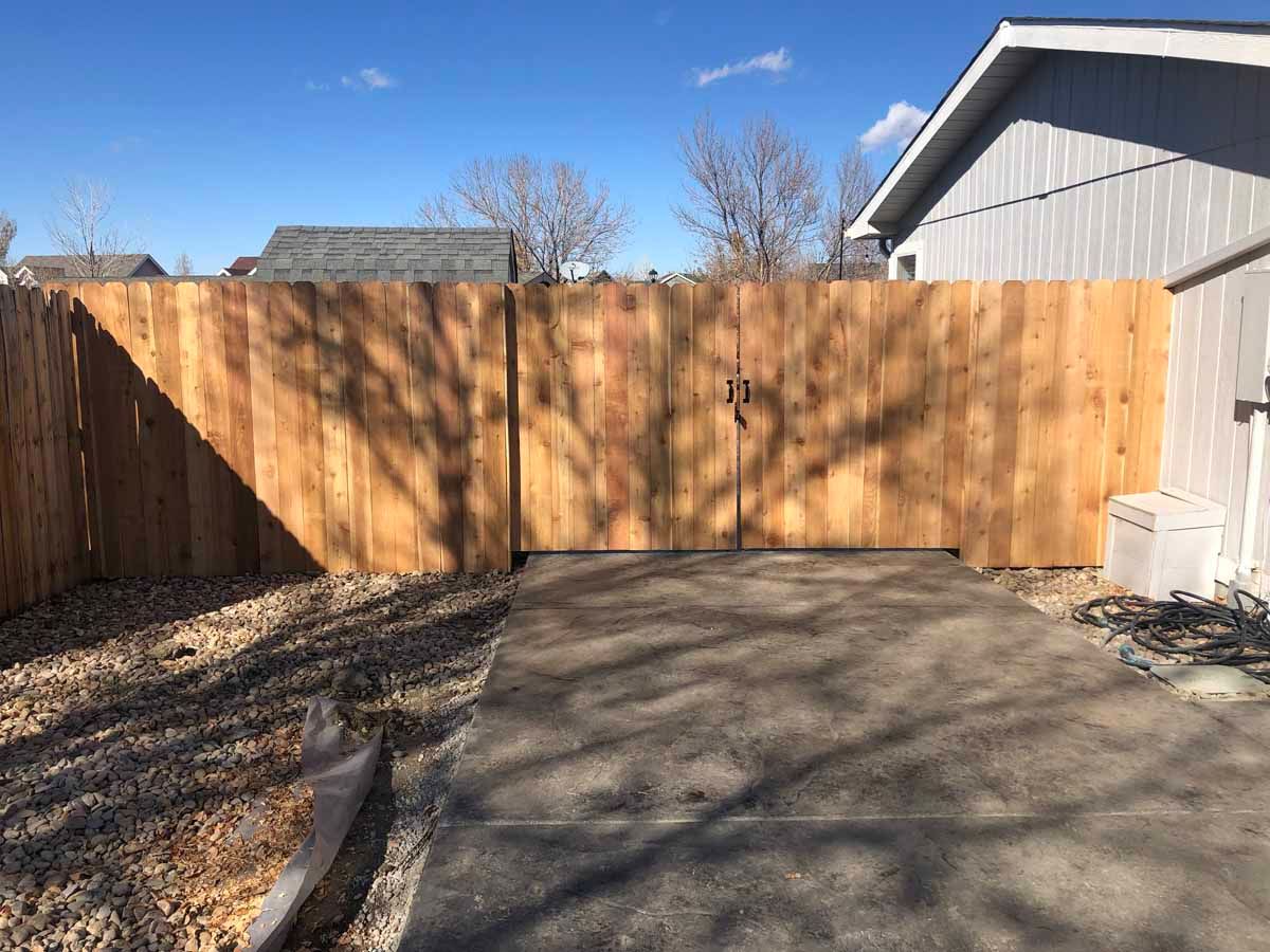 A wooden fence with a gate in the backyard of a house.