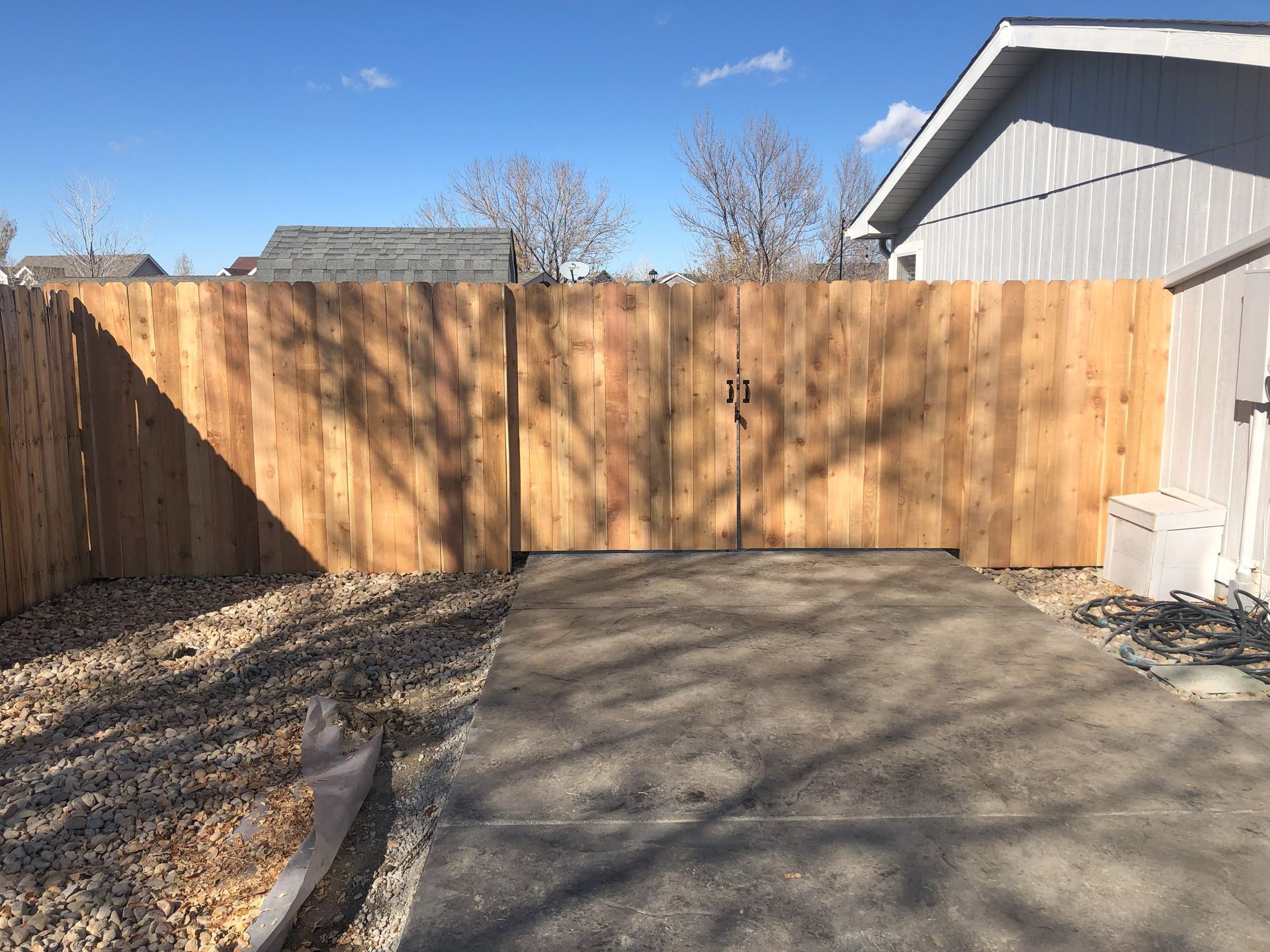 A wooden fence is surrounding a driveway in front of a house.