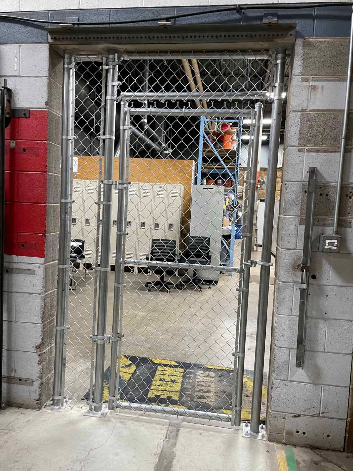 A chain link fence is surrounding a doorway in a warehouse.