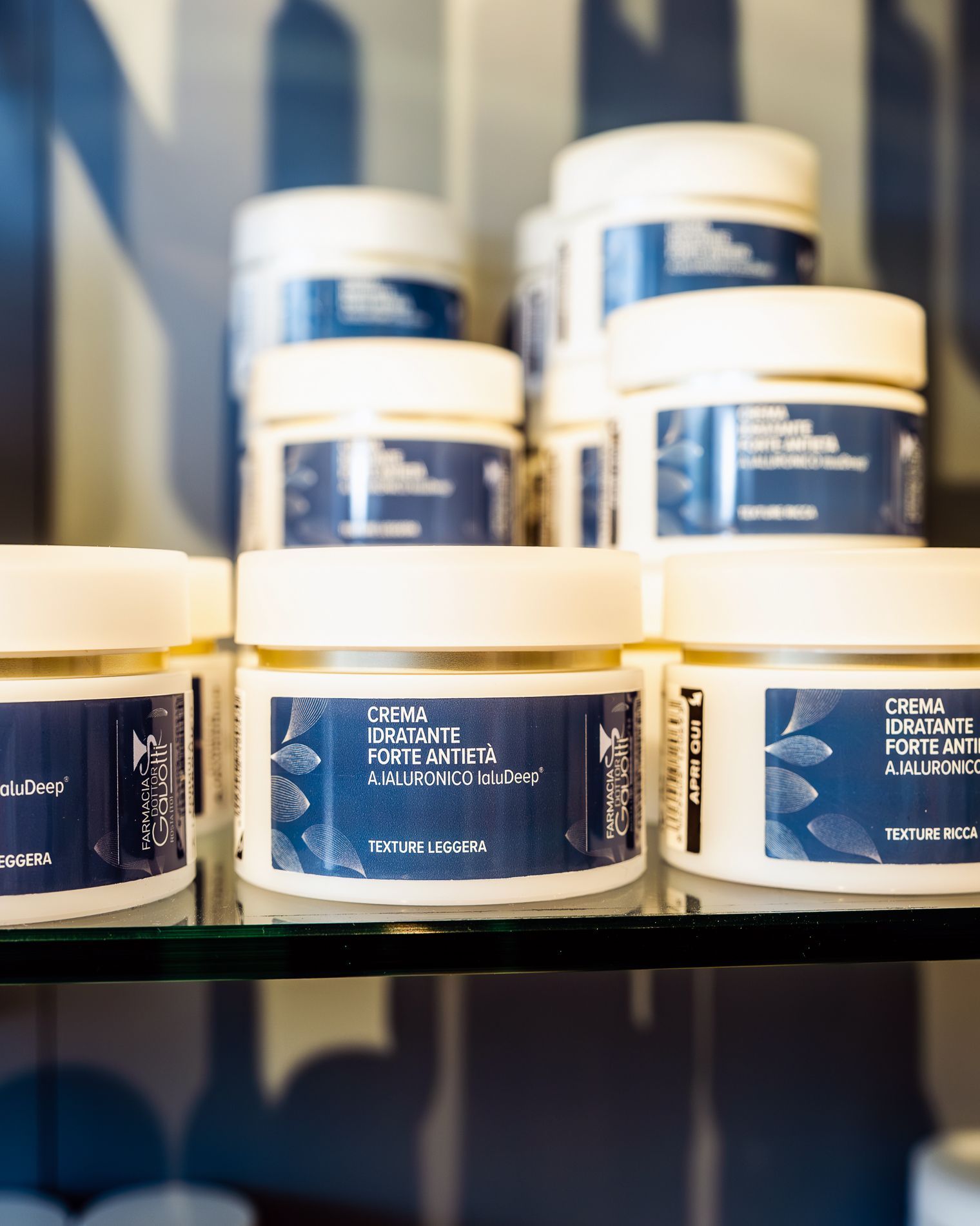 Barattoli bianchi con etichette blu sono impilati su uno scaffale di vetro