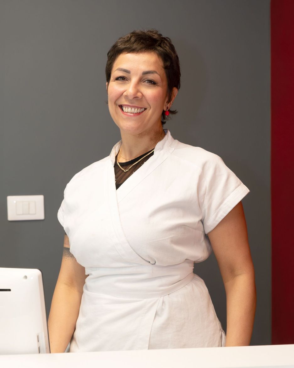 Una donna in abito bianco sorride alla telecamera