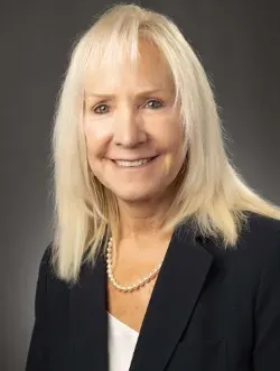 A man in a yellow vest is adjusting a thermostat while holding a tablet.
