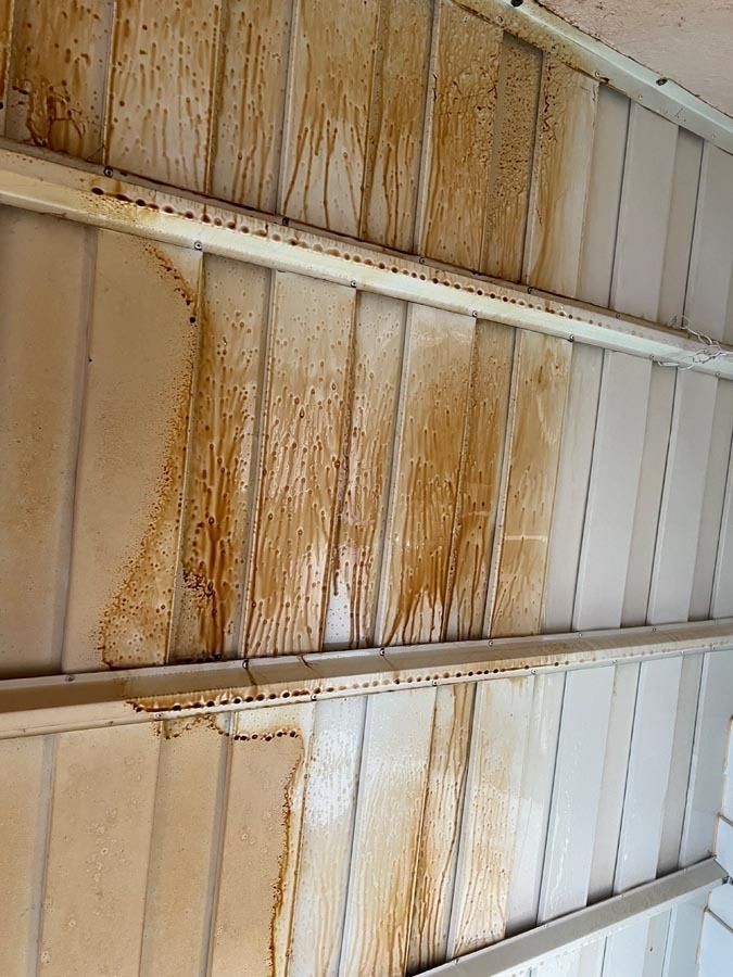 A ceiling with a lot of brown stains on it.