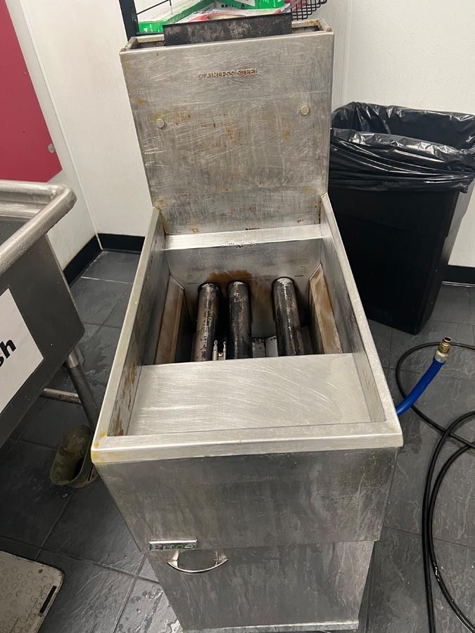 A stainless steel fryer is sitting in a kitchen next to a sink.