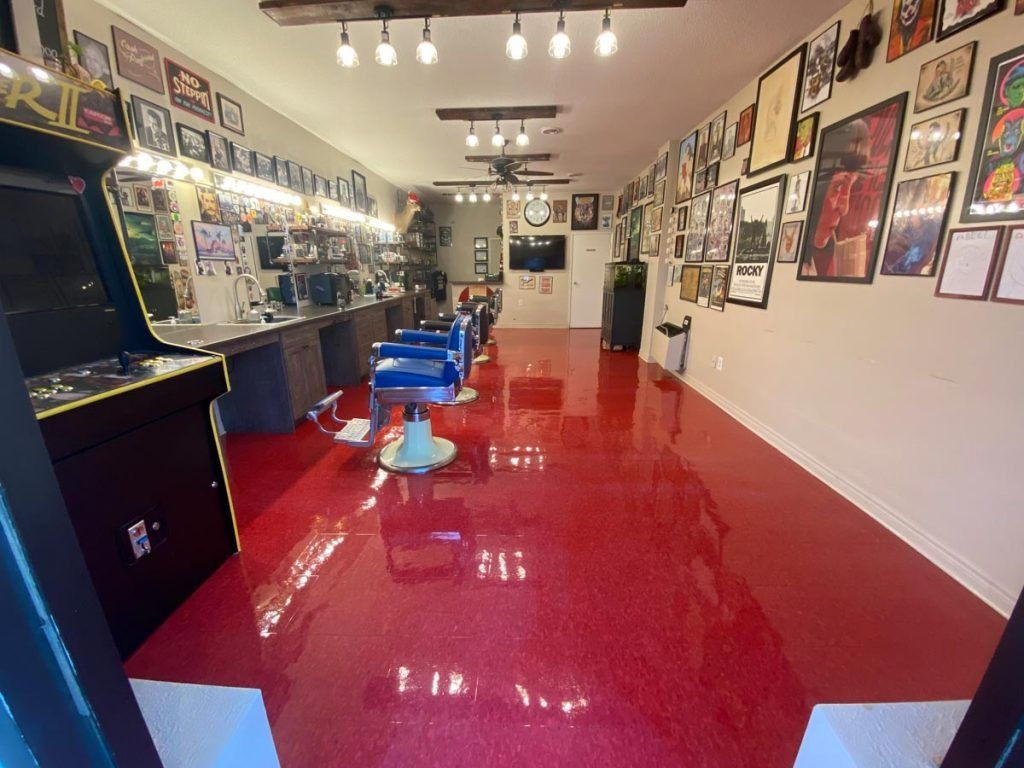 A barber shop with a red floor and a yellow arcade machine.