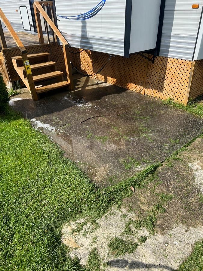 A concrete walkway next to a trailer with stairs and a hammock.