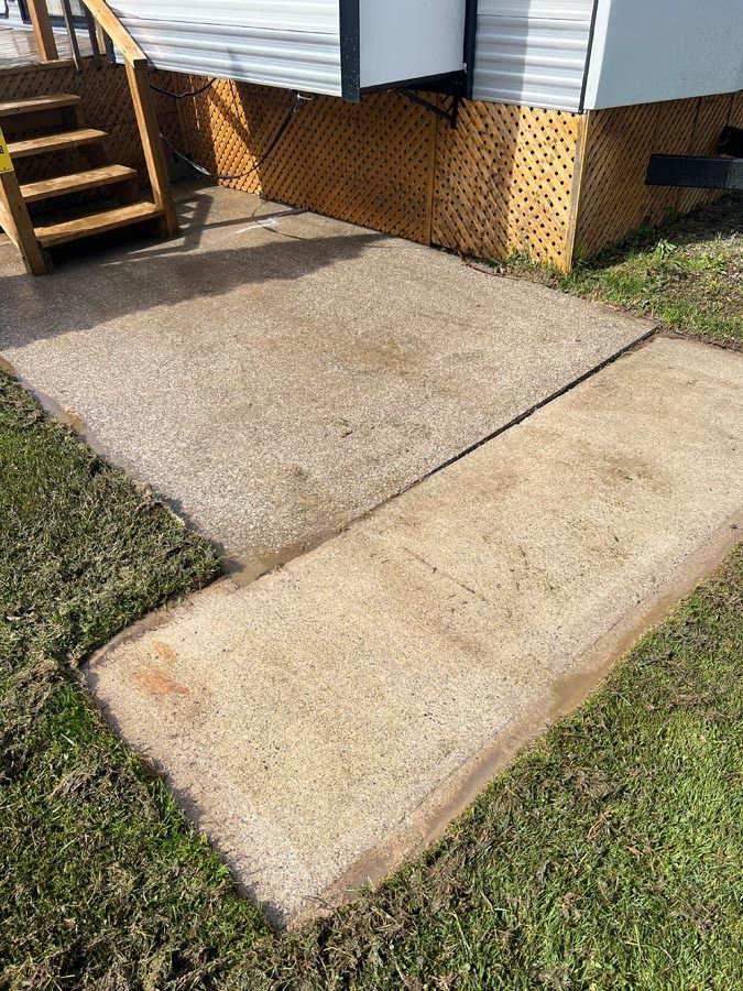 A concrete walkway leading to a trailer with stairs.