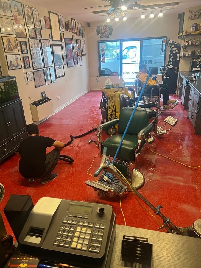 A man is cleaning a barber shop with a mop.