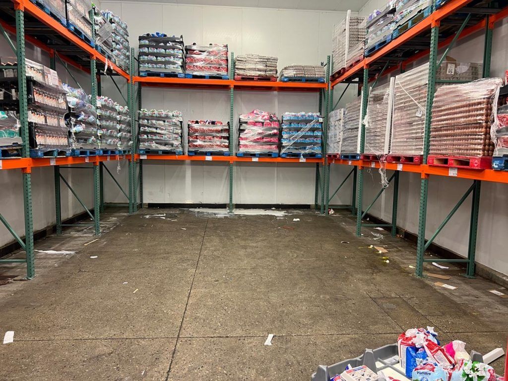 An empty warehouse filled with shelves and pallets of food.