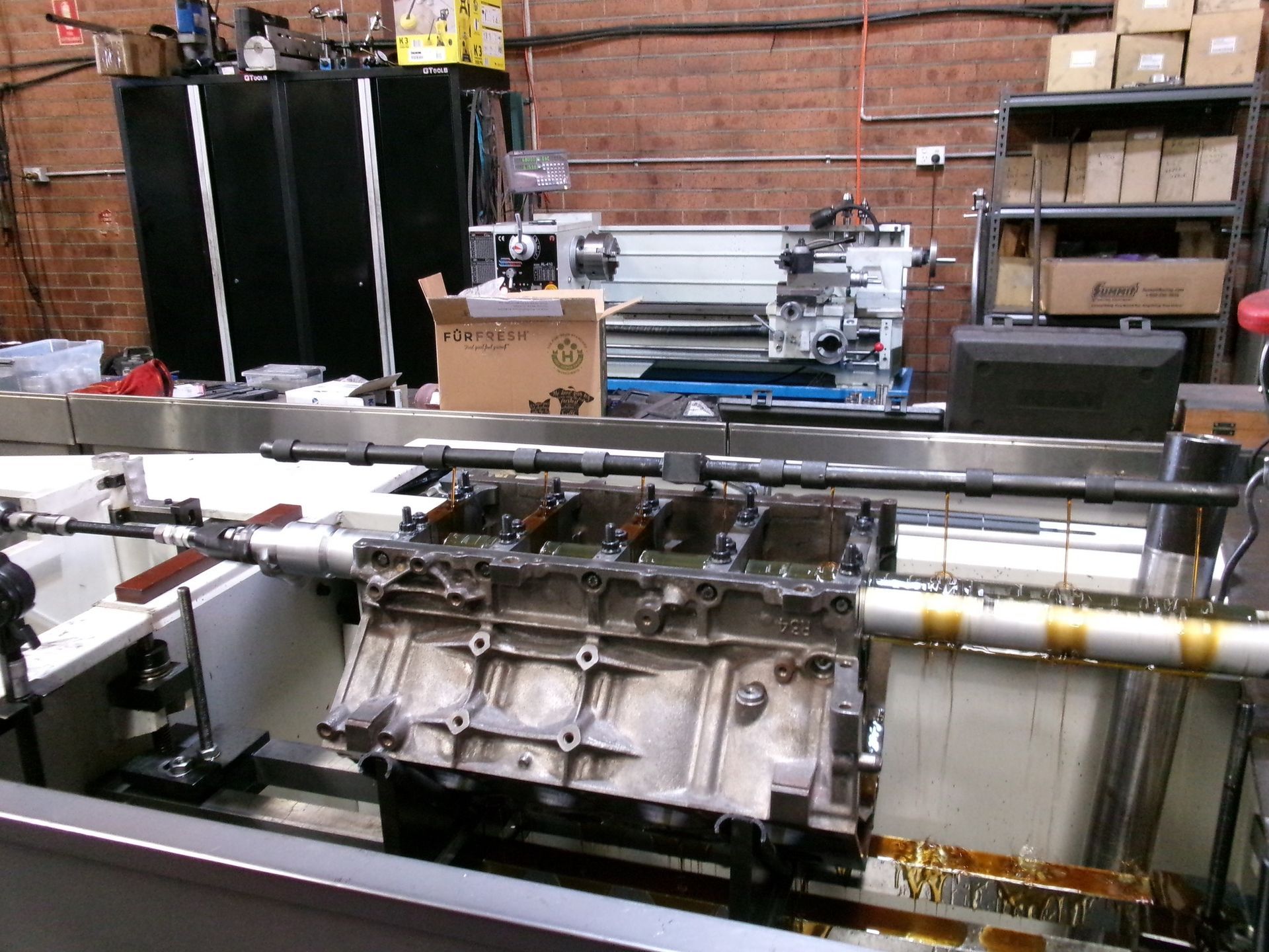 A lathe is sitting in a room next to a brick wall