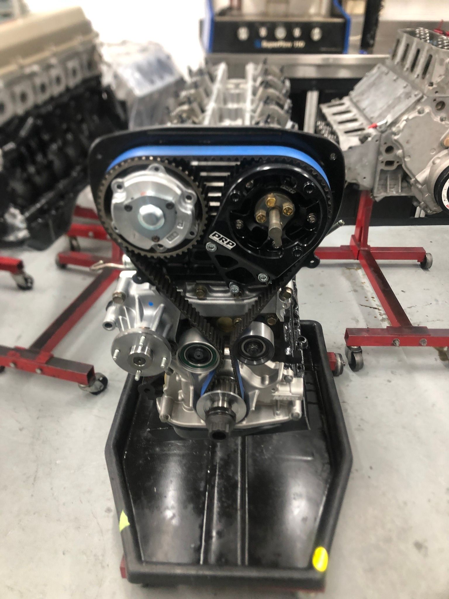 A car engine is sitting on top of a black tray in a garage.